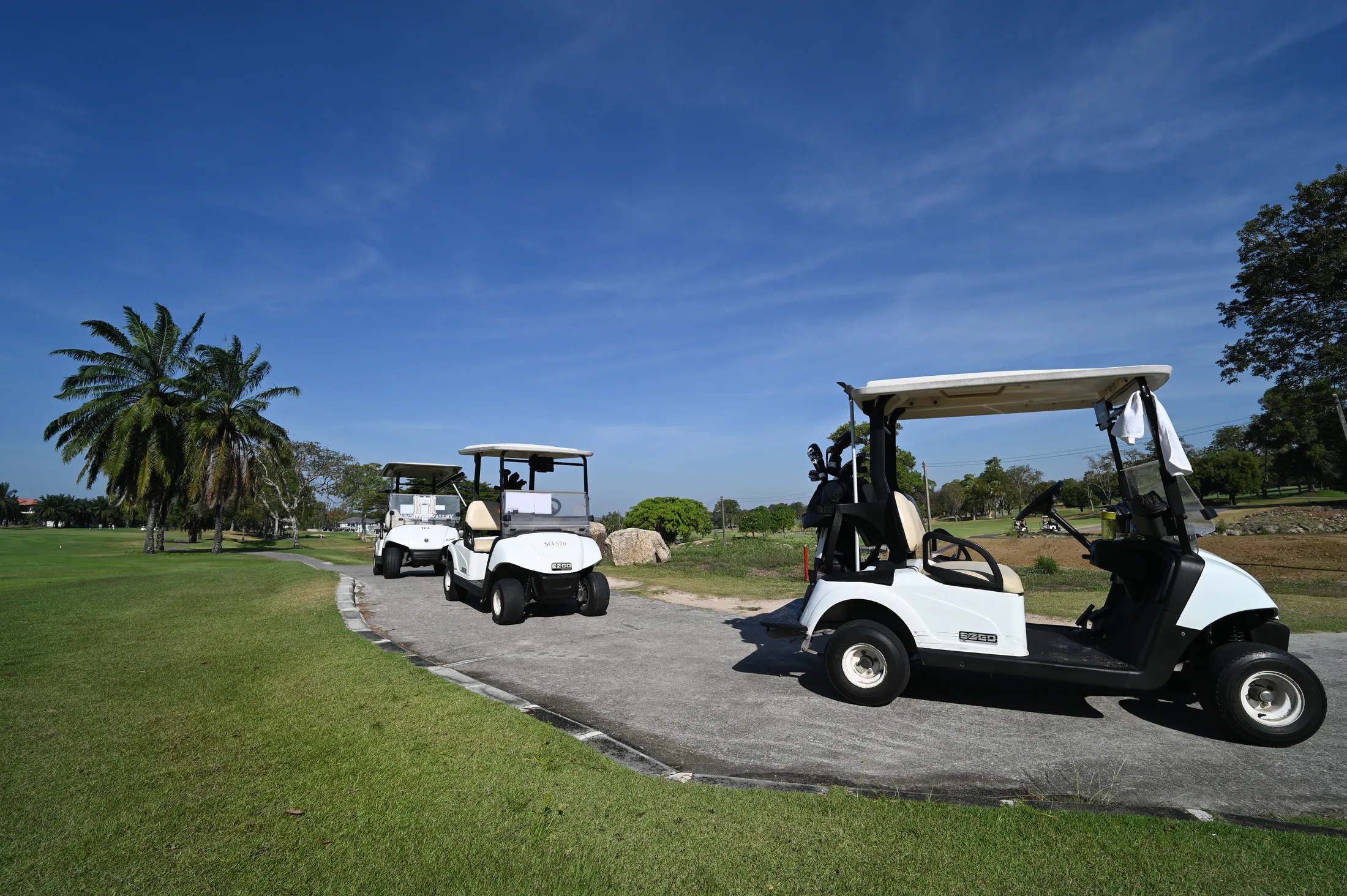 Golf carts queued together on a course cart path