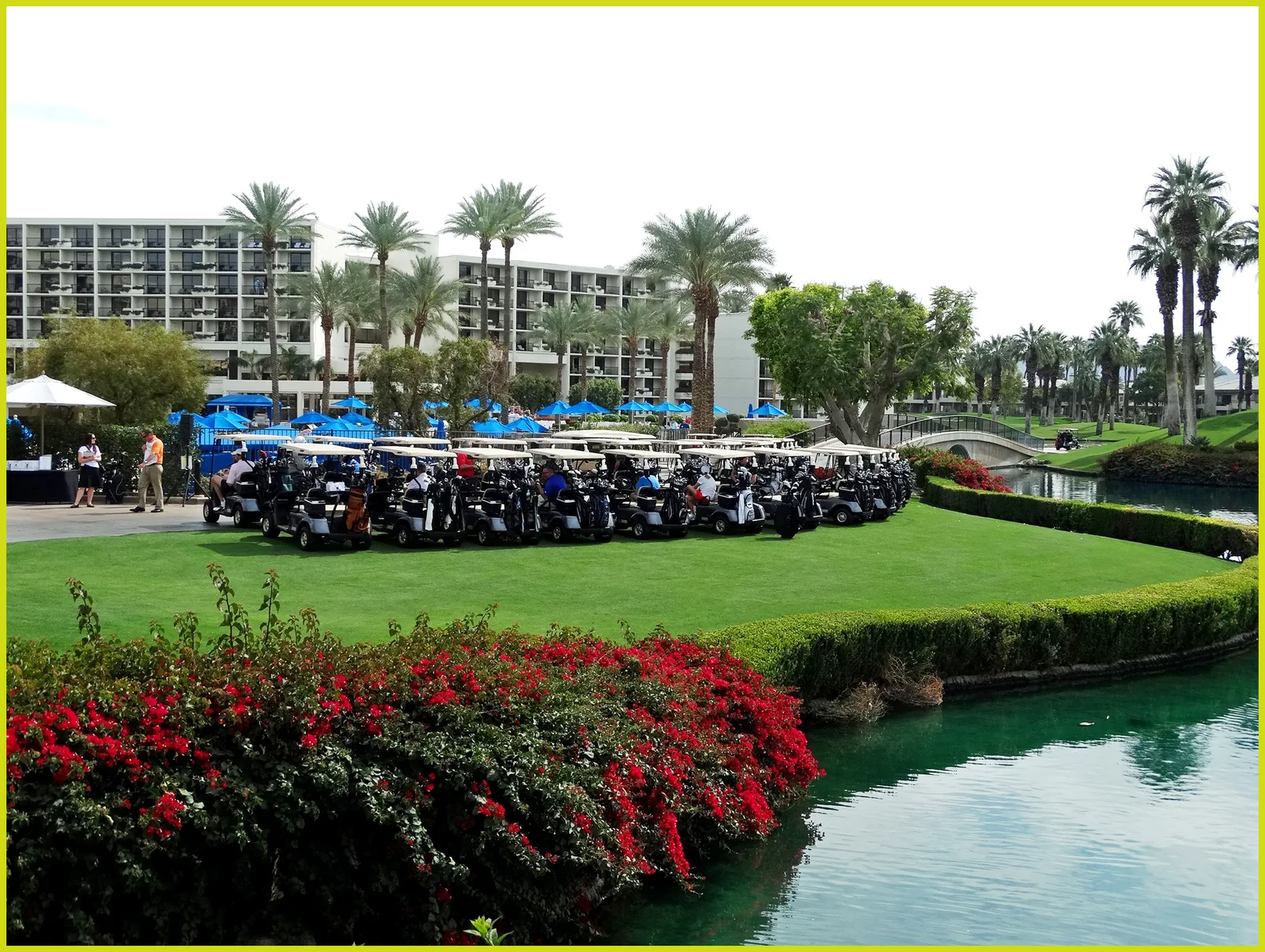 Rows of resort golf carts staged on the practice lawn, hotel tower behind