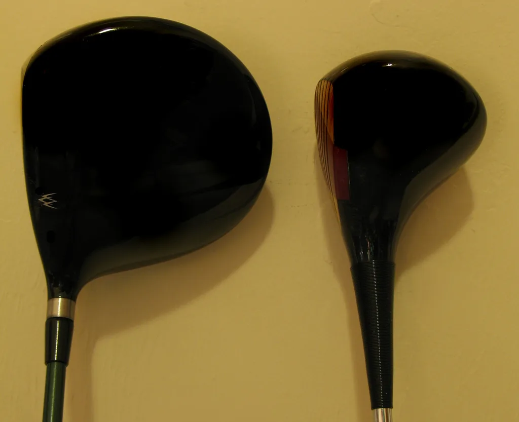 A modern 460cc metal driver next to an early persimmon-wood driver, showing how far driver technology has moved