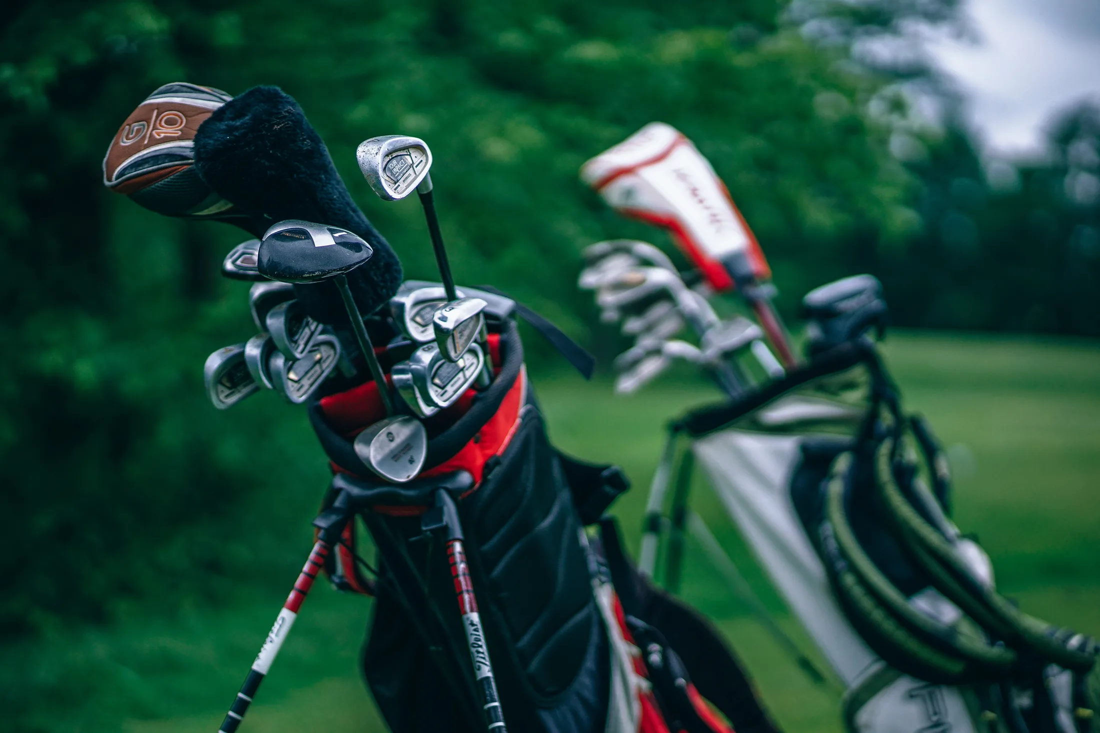Two well-used sets of irons and wedges packed bag-to-bag, headcovers and all